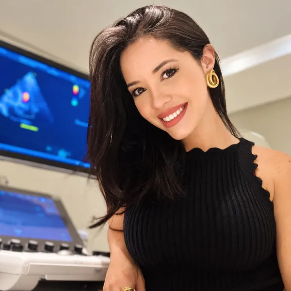 Dra. Alinne Barbosa sorrindo com o monitor do ultrassom ao fundo